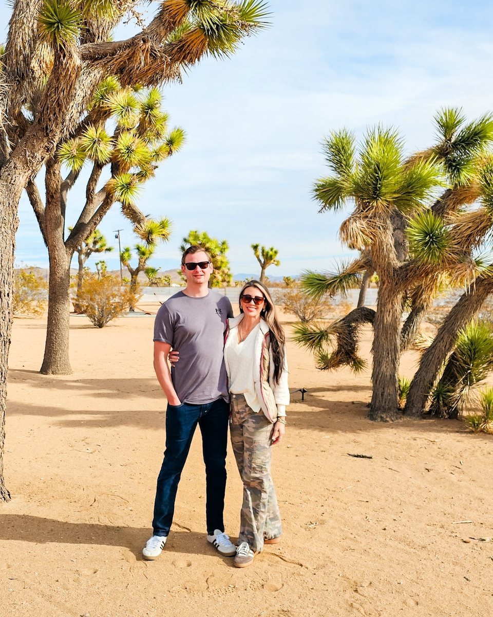 Kevin and Caroline standing among Joshua trees on a sunny day