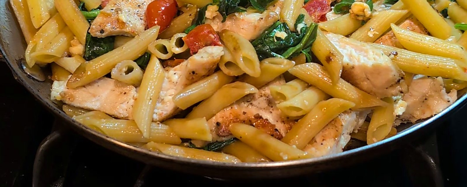 Chicken penne with cherry tomatoes and spinach in a skillet