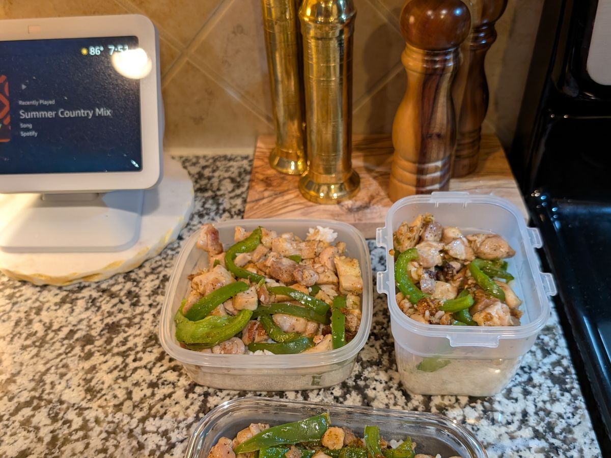 Two meal-prep containers of chicken, peppers, and rice on a kitchen counter