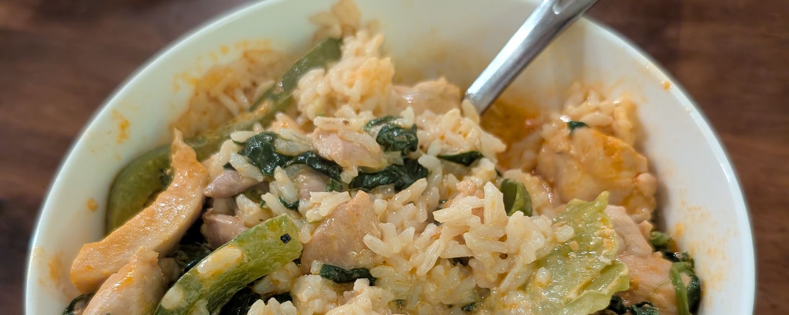 A bowl of chicken curry over rice with a spoon